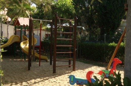 Parco giochi con scivoli e attrezzature su sabbia.