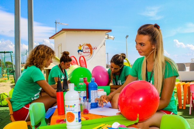 Persone sedute a un tavolo all'aperto con palloncini e materiali artistici.