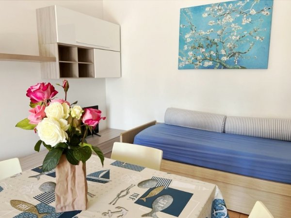 Tavolo con tovaglia stampata, vaso di fiori, divano blu e quadro floreale azzurro.
