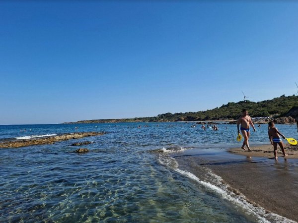 Spiaggia con mare limpido e bagnanti.