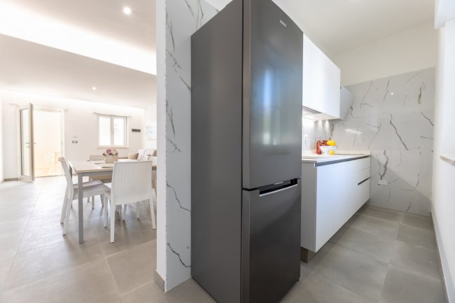 Cucina moderna con frigo nero e piano cottura bianco.