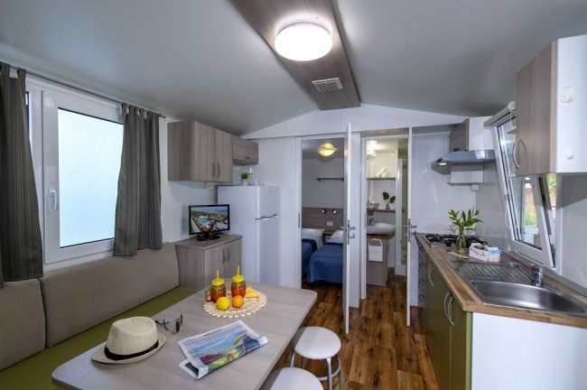 Interno di una piccola casa con cucina, tavolo e accessori da viaggio.