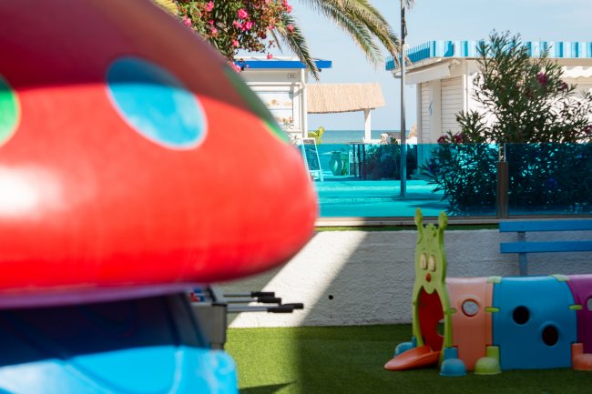 Area giochi colorata in un giardino con vista mare sullo sfondo.