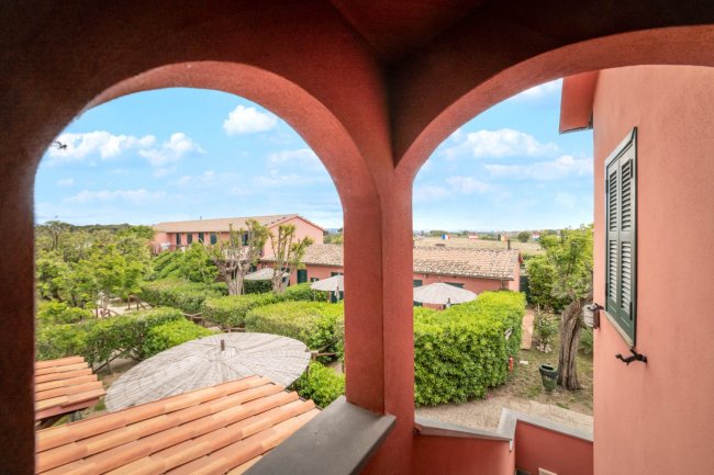 Archi di una terrazza con vista su edifici e giardino.