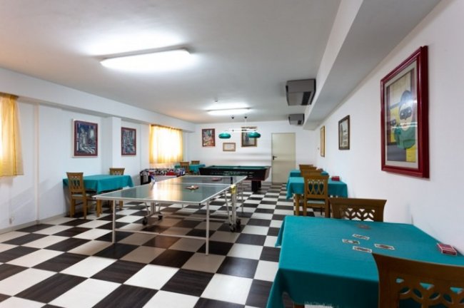 Sala con tavolo da ping pong e tavoli con tovaglie color turchese.