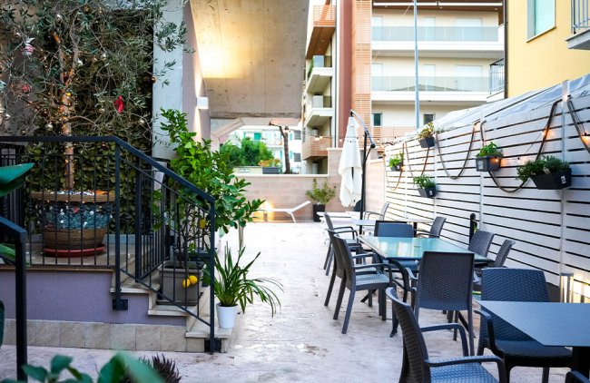 Terrazza esterna con tavoli e sedie, decorata con piante e luci.