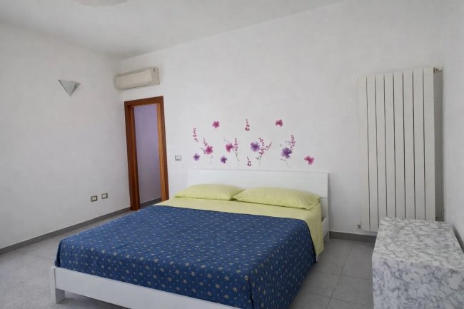 Camera da letto con letto matrimoniale e fiori sul muro.
