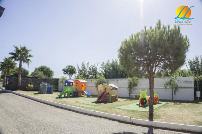 Area giochi per bambini con strutture colorate e alberi lungo la strada.