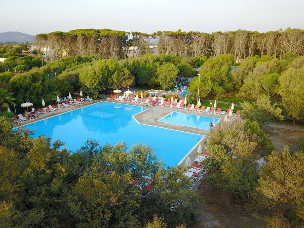Piscina con lettini e alberi circostanti.