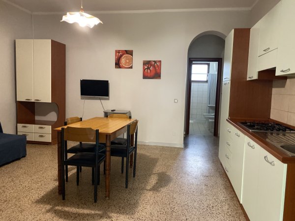 Cucina con tavolo e quattro sedie, TV a parete.