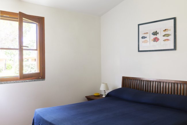 Camera da letto con letto matrimoniale blu e un quadro di pesci sul muro.