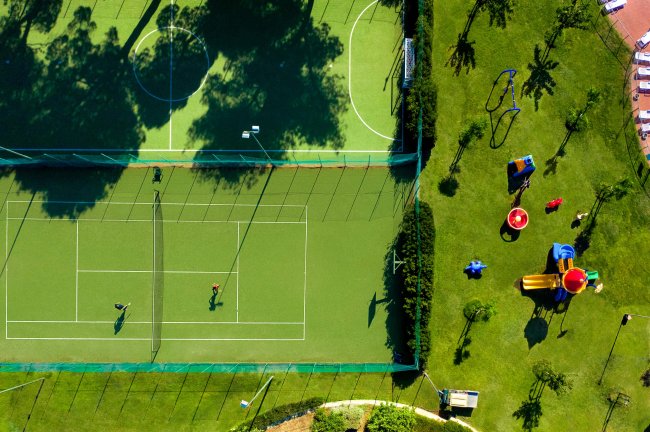 Campo da tennis e da calcio con un'area giochi verde accanto.