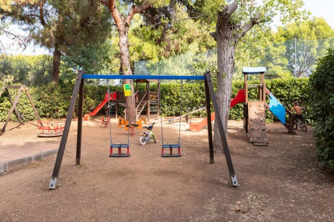 Area giochi esterna con altalene e scivoli.