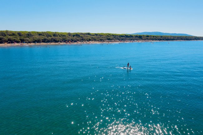 Mare azzurro con paddleboarder sotto un cielo limpido.