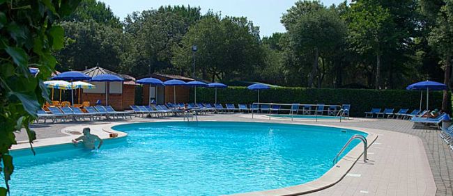 Piscina tranquilla all'aperto con lettini e ombrelloni blu.