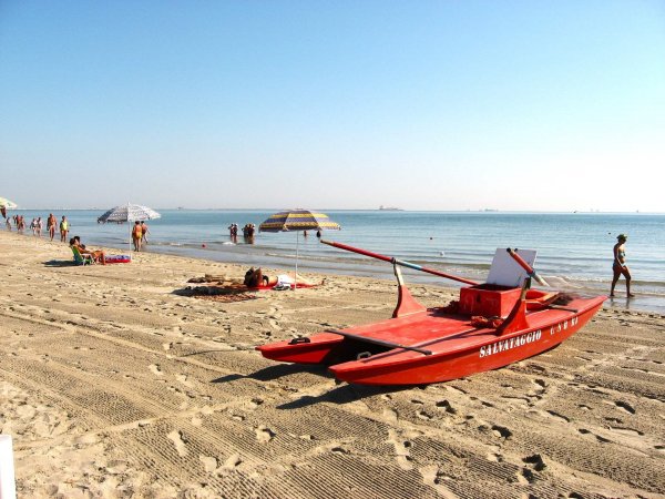 Spiaggia con barca di salvataggio e ombrelloni.