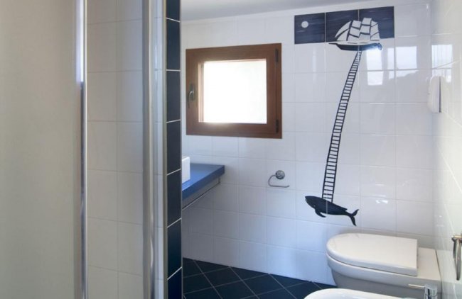 Bagno con nave e balena disegnate sulle piastrelle.