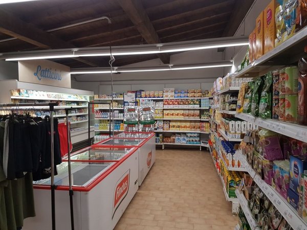 Interno di un supermercato con scaffali pieni di prodotti e un banco frigo.