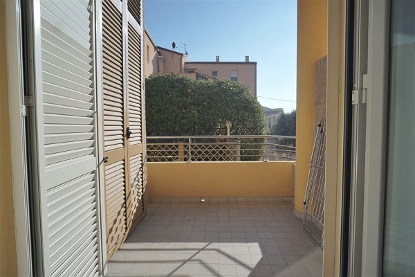 Balcone con pavimento piastrellato, ringhiera in metallo e vista su altre abitazioni.