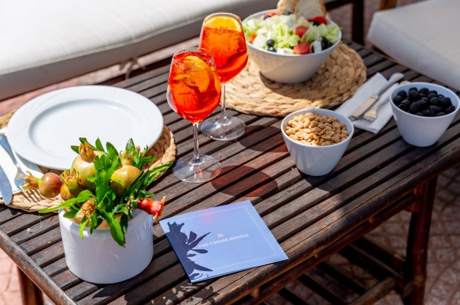 Tavolo con bevande arancioni, insalata, snack, e decorazioni.
