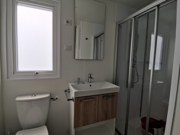 Bagno moderno con finestra opaca, lavabo, specchio, doccia e wc.