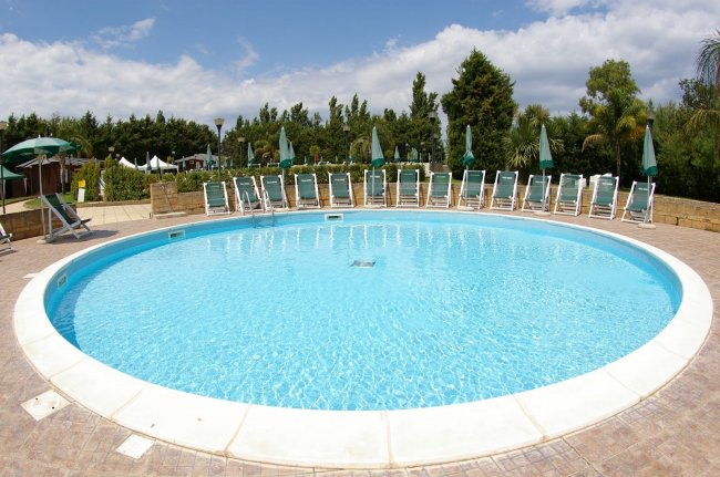 Piscina rotonda con sedie a sdraio.