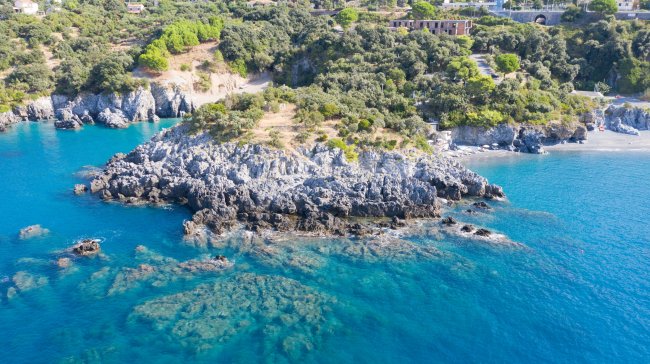 Costa rocciosa con acqua cristallina e vegetazione.
