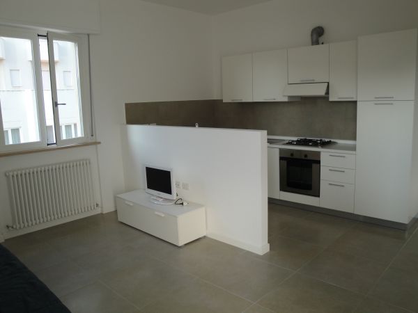 Cucina moderna bianca con piccolo televisore.