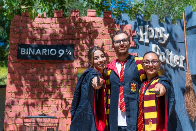 Tre persone in costumi da maghi davanti a un set di Harry Potter.