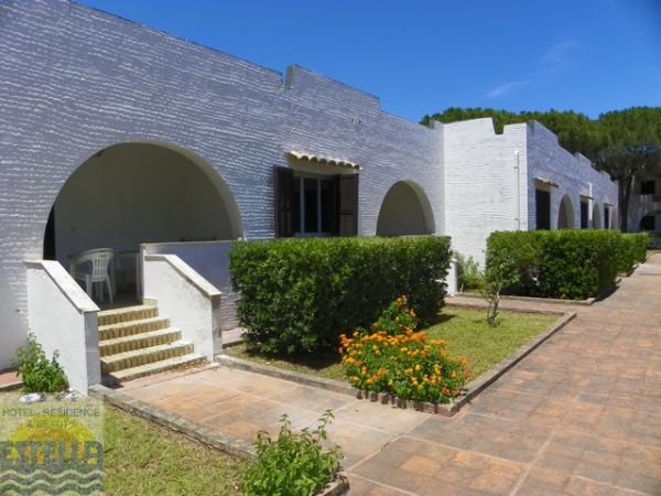 Edificio bianco con archi e giardino fiorito sul davanti sotto un cielo blu.