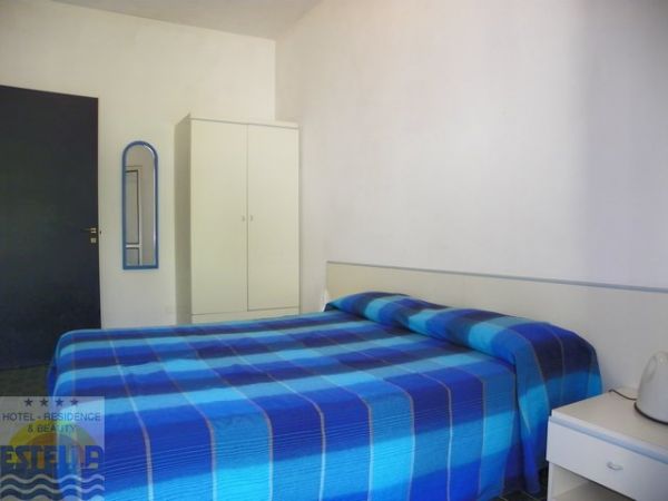 Camera con letto matrimoniale e copriletto a righe blu.