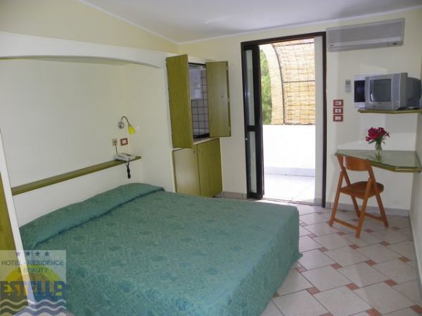 Camera d'albergo con letto matrimoniale, scrivania e porta finestra.