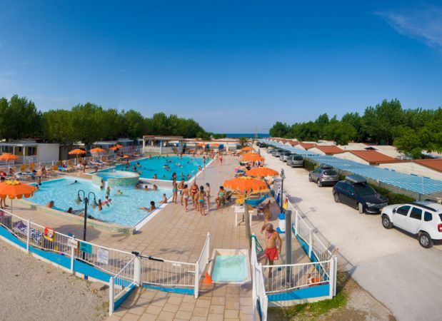 Piscine all'aperto con ombrelloni arancioni, persone che nuotano e relax.