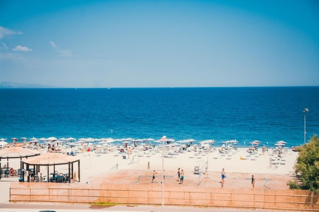 Spiaggia con ombrelloni e mare azzurro.
