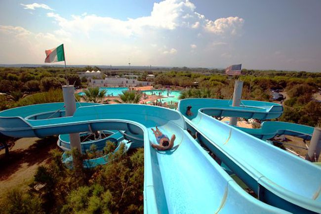 Uomo su uno scivolo blu in un parco acquatico, vista dall'alto.