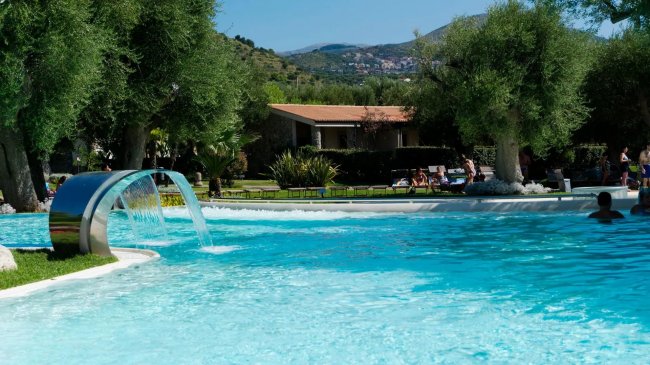 Piscina con fontana circondata da alberi.
