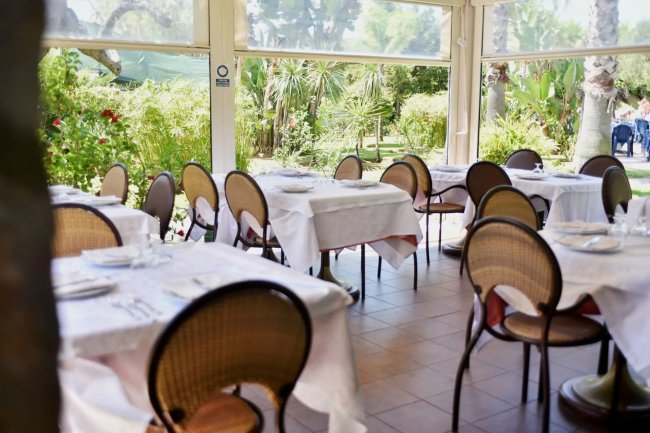 Tavoli apparecchiati in una veranda fiorita.