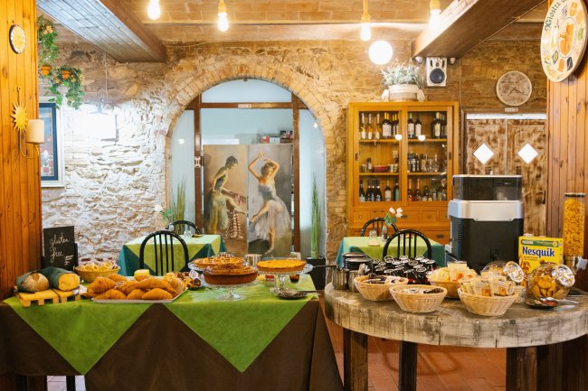Buffet di dolci e cereali su tavoli verdi in una sala interna con muri in pietra.