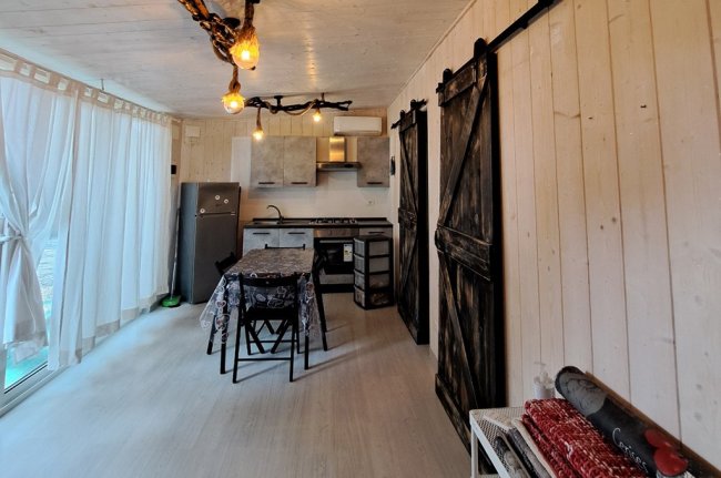 Un interno di cabina con cucina, tavolo e porte di legno scuro.