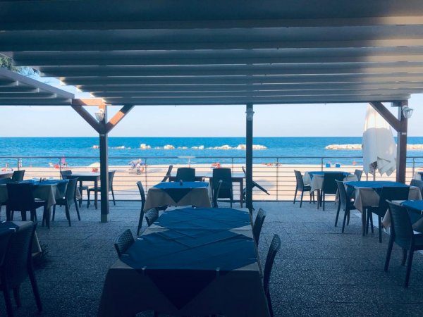 Una terrazza ristorante con vista sul mare e ombrelloni.
