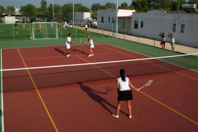 Tre persone giocano a tennis su un campo all'aperto.