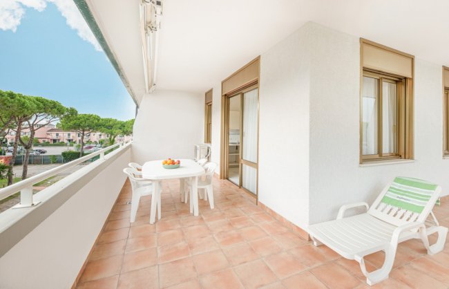 Balcone con tavolo bianco, sedie e lettino, vista esterna.